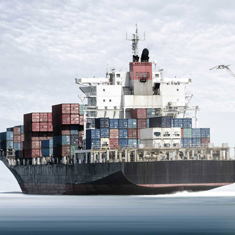 Large cargo ship loaded with colorful containers, sailing on a calm sea.